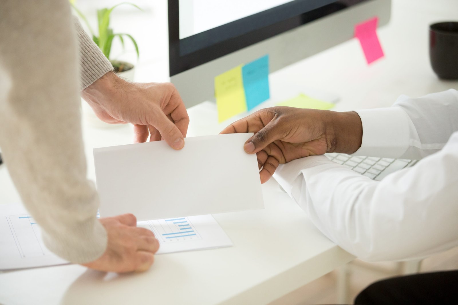 Pic: Businessman receiving bribe or money bonus from partner client boss at work, bribery in business, corruption or employee reward concept, close up view of hands with envelope.